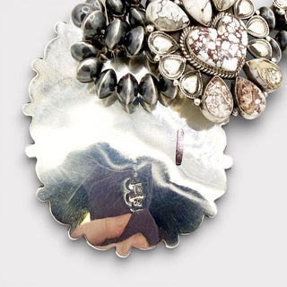 Close-up of a silver pendant with textured surface and embedded photo, on a white background.