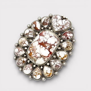 Decorative brooch with central stone and silver accents on a light gray background