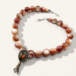orange beaded necklace with pendant on a beige background