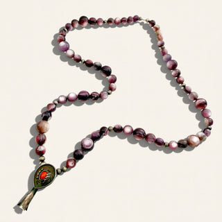purple beaded necklace with pendant on a beige background