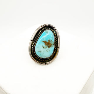 Turquoise stone ring with silver and gold accents on a white background
