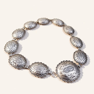 A silver-toned concho-style bracelet with multiple oval links displayed on a clean off-white background.