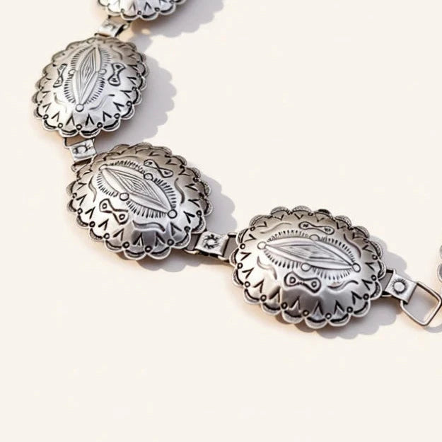 Silver jewelry with concho design on a beige background