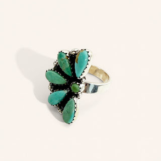 Turquoise ring with silver band on a light beige background