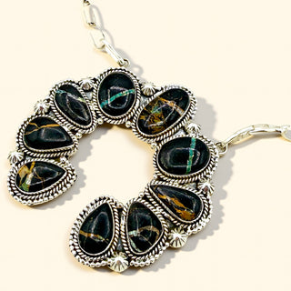 Silver necklace with black gemstones on a white background