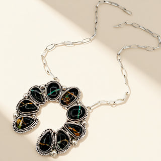 Silver necklace with black stone pendant on a beige background