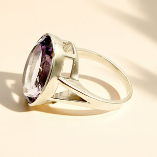 Silver ring with a purple gemstone on a beige background