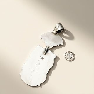 Silver pendant with a white stone on a beige background
