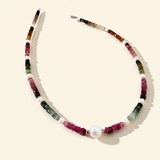 Necklace with multicolored beads and a pearl on a beige background
