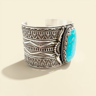 Silver cuff bracelet with turquoise stone on a beige background