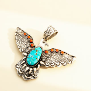 Thunderbird pendant with turquoise and red stones on a beige background