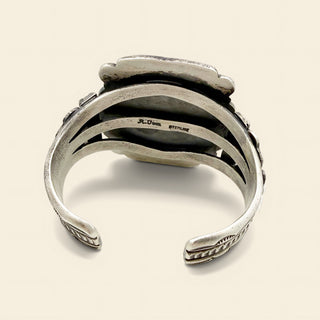 Silver cuff with intricate design on a beige background