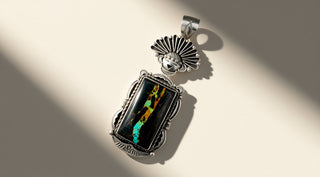 Silver pendant with intricate designs on a beige background