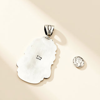 Silver pendant and coin on a beige background