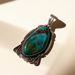 Turquoise stone pendant with silver setting on a beige background