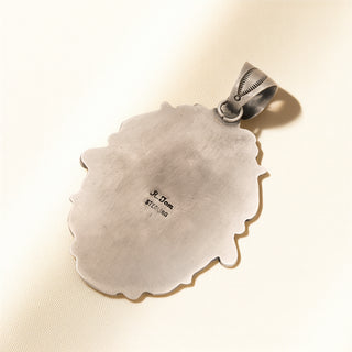 Silver pendant with stamp on a beige background