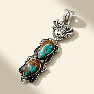 Silver pendant with brown and turquoise stones on a beige background