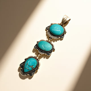 Turquoise stone pendant with silver accents on a beige background