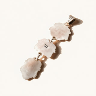 Jewelry pendant with three shell-like stones on a white background