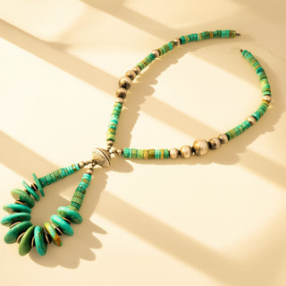 Necklace with green and gold beads on a beige background