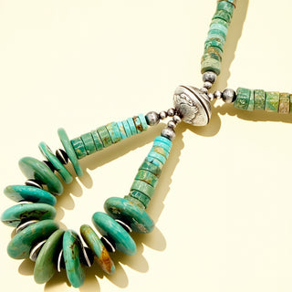Turquoise beaded necklace with silver accents on a beige background