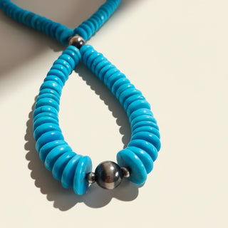 Turquoise beaded necklace with silver accents on a light background