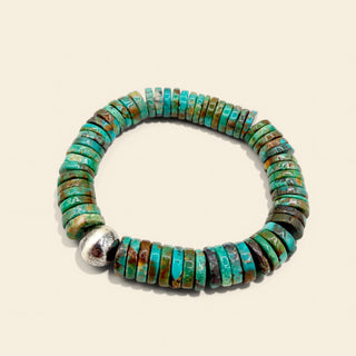 Turquoise beaded bracelet with a silver clasp on a beige background