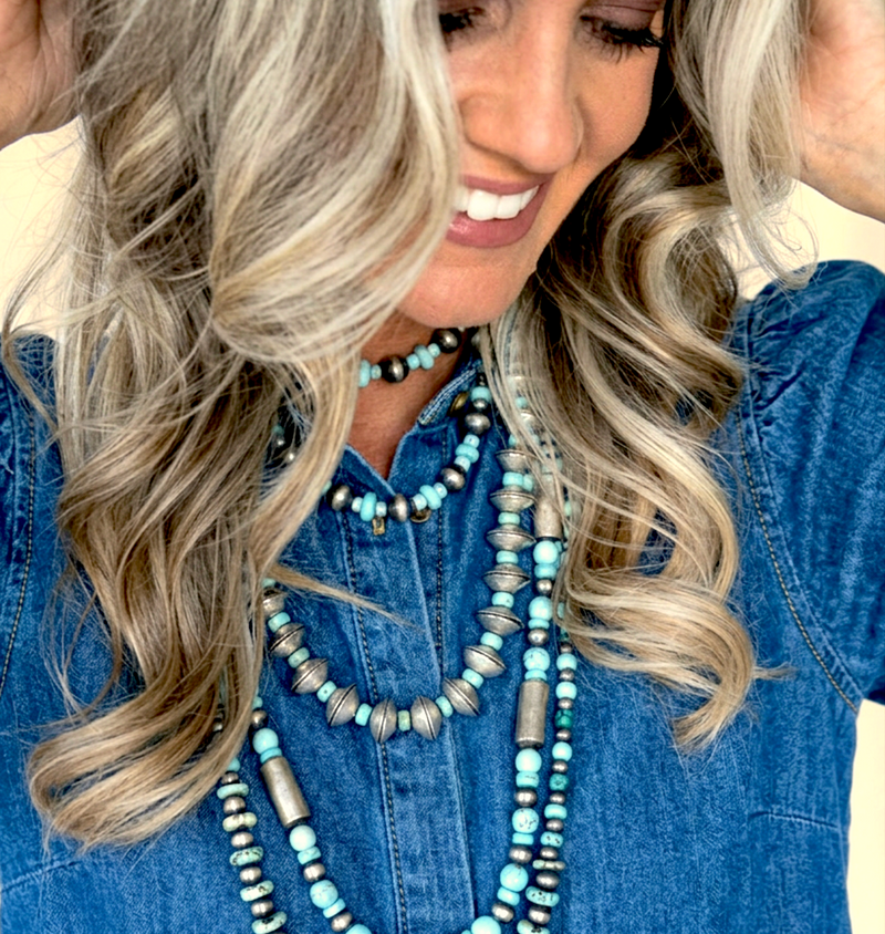 Woman wearing multiple necklaces with a denim shirt