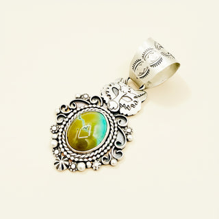 Silver pendant with green stone on a beige background