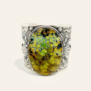 Cuff bracelet with a green and black marbled stone and silver detailing on a white background