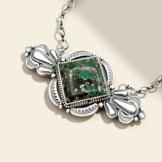 Silver necklace with a green stone pendant on a beige background
