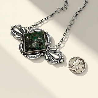 Silver necklace with a pendant and coin on a light background