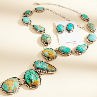 Turquoise stone necklace with matching earrings on a beige background