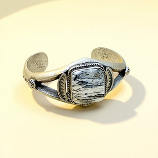 Silver cuff with a white stone on a beige background