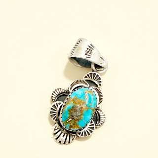 Silver pendant with a turquoise stone on a beige background