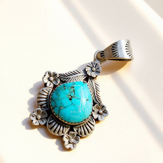 Silver pendant with turquoise stone on a white background