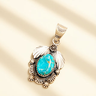 Silver pendant with a turquoise stone on a beige background