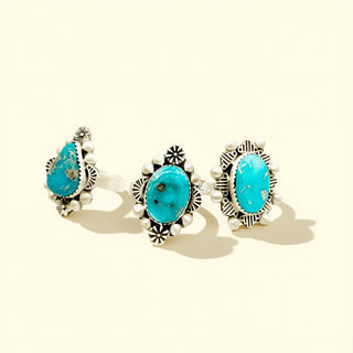 Three pairs of rings with turquoise stones on a beige background