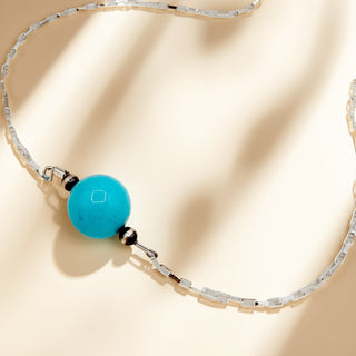 Necklace with a blue bead on a beige background