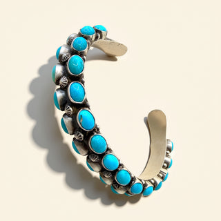 Silver  cuff with turquoise stones on a beige background