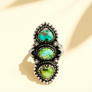 Silver ring with green stones on a beige background