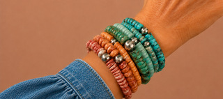 Close-up of a wrist wearing multiple colorful beaded bracelets on a brown background