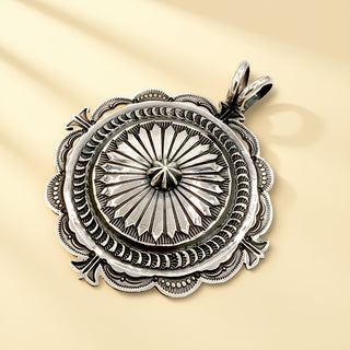 Silver pendant with intricate designs on a beige background