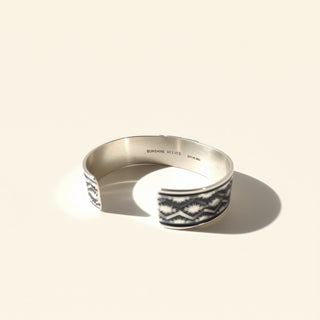 Silver ring with black and white pattern on a beige background