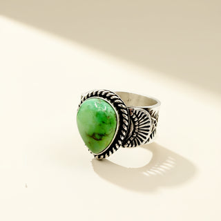 Silver ring with a green stone on a beige background