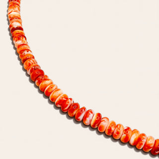 orange beaded jewelry on a beige background