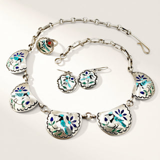 silver jewelry set with blue bird symbols on a beige background