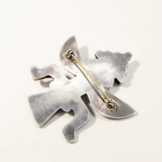 A silver-toned metal pin featuring a stylized, abstract bird or winged creature silhouette, shown from the back on a plain off-white background.