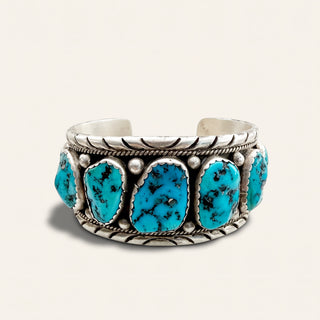 silver cuff with turquoise stones on a beige background
