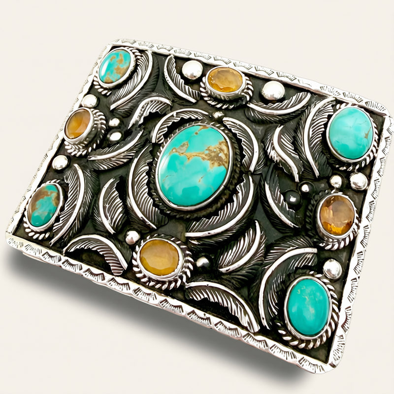Decorative silver belt buckle with turquoise and amber stones on a white background